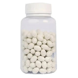 Clear bottle filled with white oval candies on a white background